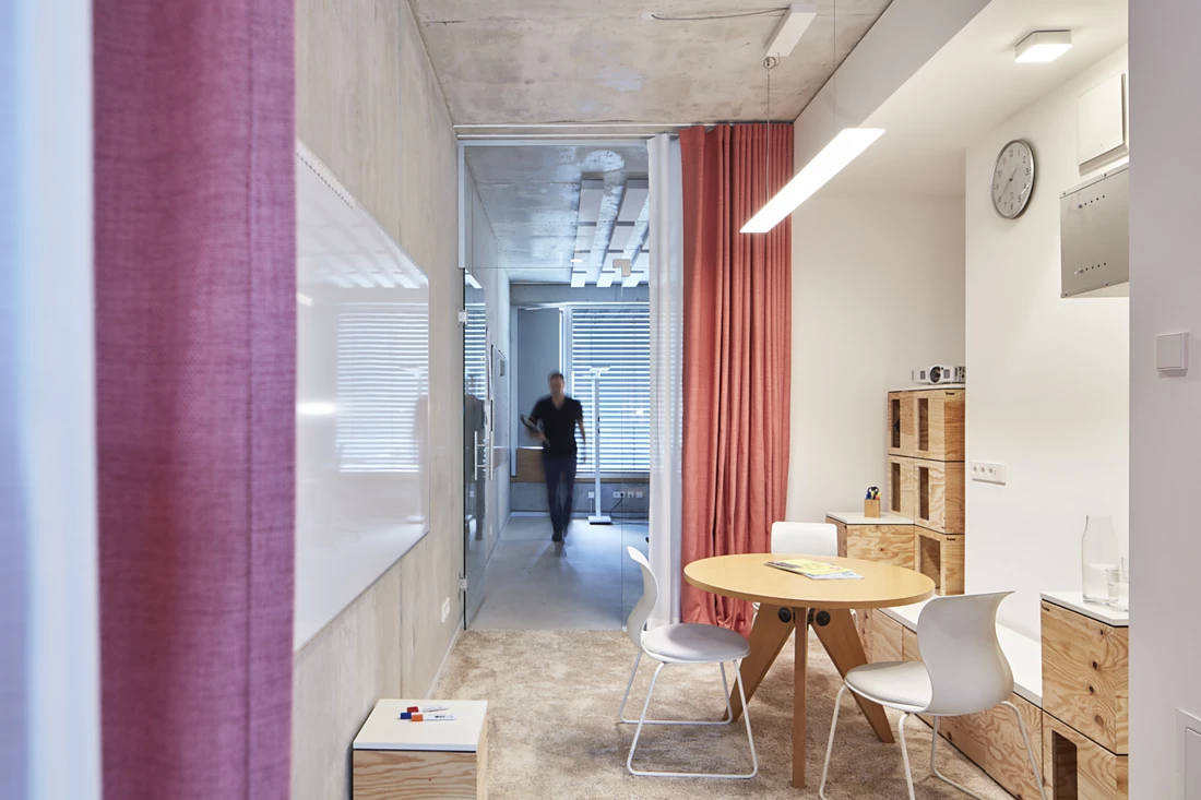 Exposed concrete and glass dominate the new floor of offices. Highlights are set by coloured curtain fabrics and furniture made of light-coloured wood. Photo: ©Koy+Winkel