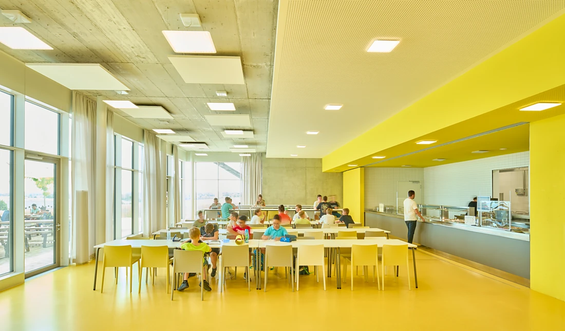 <p><span>The vibrant yellow of the canteen is intensified by the daylight entering through the large, floor-to-ceiling windows. When daylight conditions are poor, square Nimbus Modul Q Project luminaires create the same effect &ndash; and on the ceiling they set aesthetic accents and provide uniform lighting. Photo: David Matthiessen</span><span></span></p>